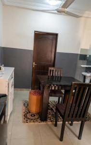 a kitchen with a table and a chair and a door at BKSF Wemtenga 1 in Ouagadougou