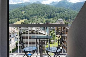 a balcony with a table and chairs and mountains at Bertuzzi Homes in Aprica