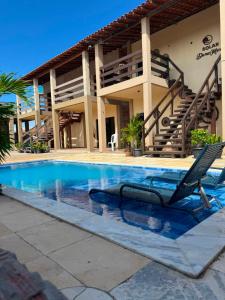 a swimming pool with a chair in front of a house at Solar DorisMar in Luis Correia