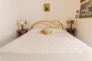a bedroom with a white bed with a gold headboard at Brezza dell'Argentario in Porto Santo Stefano