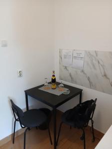 a table with two chairs and a bottle of wine on it at Аpartman CACA in Pančevo