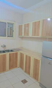 a kitchen with wooden cabinets and a white refrigerator at أمواج البحر حي البوادي in Jeddah