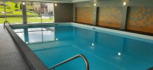 a swimming pool with blue water in a building at Appartement Plein Soleil in Les Rousses