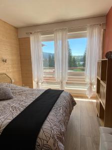 a bedroom with a bed and a large window at Appartement Plein Soleil in Les Rousses