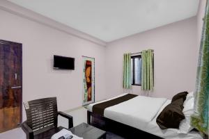 a bedroom with a bed and a table and a chair at Hotel O Candel Light Inn in Bhubaneshwar