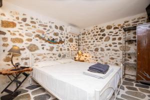 a bedroom with a white bed and a stone wall at Villa Sofia in Evkarpía