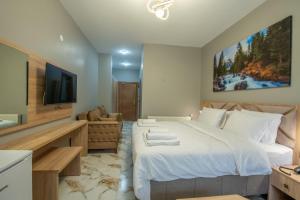 a bedroom with a large white bed and a television at Demirkapı Otel in Uzungöl