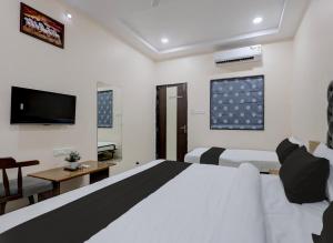 a hotel room with two beds and a television at Super HOTEL O MATRI CROWN in Raipur