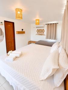 a bedroom with a large white bed with two pillows at Atins Suites in Atins