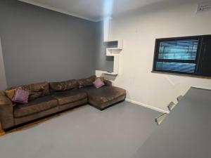 a living room with a brown couch and a window at Blue Moon Guest Rooms in Bellville +30 photos