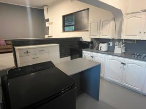 a kitchen with white cabinets and a black refrigerator at Blue Moon Guest Rooms in Bellville