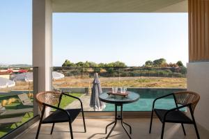 a balcony with a table and chairs and a large window at Pnoe Boutique suites in Nikiti