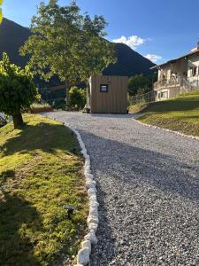 a gravel road with a tree and a building at Everest Experience in Paluzza