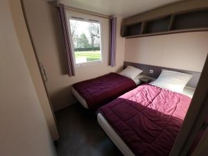 two beds in a small room with a window at Camping Les Goélands Carnac in Plouharnel