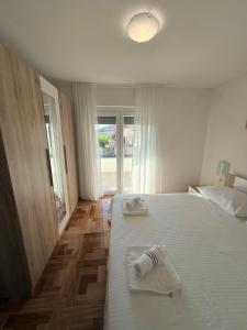 a white bedroom with two beds and a window at Apartmani Lucija 3 in Zubovići
