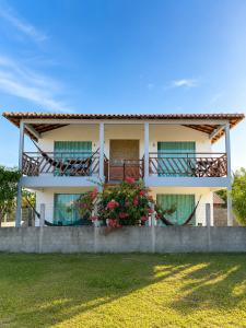 a white house with a balcony with flowers on it at Atins Suites in Atins