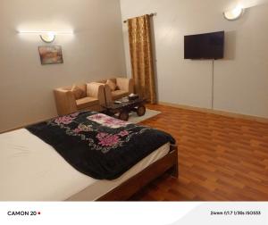a bedroom with a bed and a couch and a television at Hotel Royal Inn in Karachi
