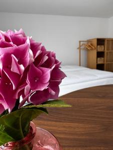 a vase with purple flowers in a room with a bed at Domek pod Jabłonią in Barzowice