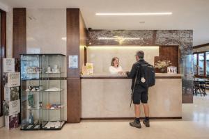 a man standing at a counter talking to a woman at Hotel Mogay in Chantada