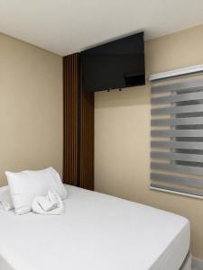a bedroom with a white bed with a flat screen tv at Hotel Castillo in San Pedro Sula