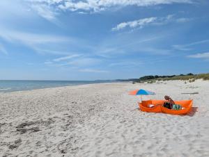 a person sitting in an orange boat under an umbrella on the beach at Glemminge Bed & Bastu in Glemminge +22 photos