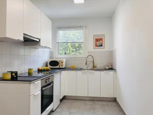 a white kitchen with a sink and a microwave at Paris Bercy with car park by Melvane in Charenton-le-Pont