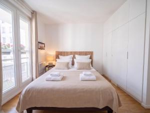 a bedroom with a large bed with two towels on it at Paris Bercy with car park by Melvane in Charenton-le-Pont +6 photos