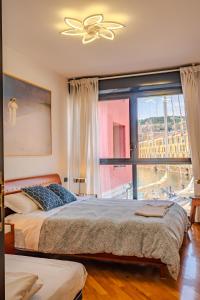 a bedroom with two beds and a large window at APPARTAMENTO SUL MARE KATE in Genoa
