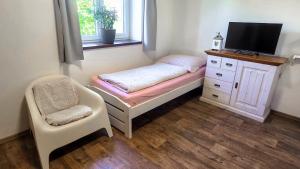 a small bedroom with a bed and a chair at Penzion Domanín in Třeboň