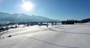 um campo coberto de neve com o sol no céu em Chalet Findeisen em Ramsau am Dachstein
