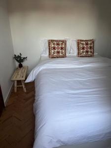a large white bed with two pillows and a table at Casa do Sol in Pedrógão