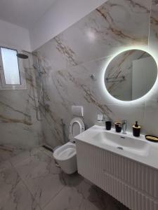 a bathroom with a sink and a toilet and a mirror at Sunset Bliss Apartments in Sarandë