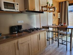 a kitchen with a stove and a table with a microwave at Maisonnette cosy au calme avec jardin clos - Puy dufou in La Ronde +7 photos