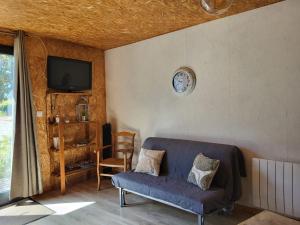 a living room with a couch and a clock on the wall at Maisonnette cosy au calme avec jardin clos - Puy dufou in La Ronde