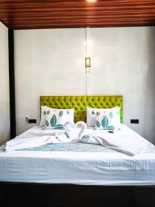 a bedroom with a white bed with a yellow headboard at Rhythm Beach in Trincomalee +7 photos
