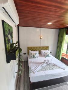 a bedroom with a white bed with a wooden ceiling at Rhythm Beach in Trincomalee