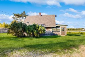 a house on a lawn with a tree at Peaceful coastal cabin with screened porch, water view of the cove, dog-friendly in Owls Head