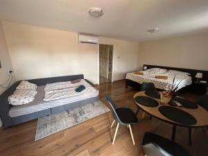 a bedroom with two beds and a table and chairs at Summer Apartments in Tiszakécske
