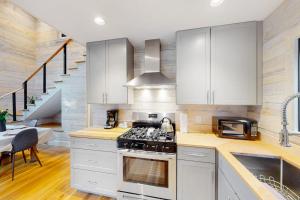 a kitchen with white cabinets and a stove top oven at Contemporary retreat with grill, firepit, & patio - walk to beach in Marlboro