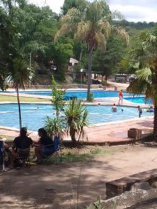 three people sitting in chairs in front of a swimming pool at El Espinillo in La Falda