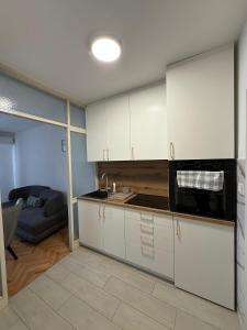 a kitchen with white cabinets and a black microwave at ZoViTe apartment in Topla