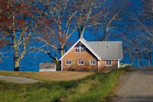 a house on the side of a hill with trees at Remodeled Waterfront Home with Wraparound Deck, Water Views, & Beach Access in Waldoboro
