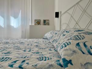 a bed with a blue and white quilt on it at Colibrì by SolturElba in Capoliveri