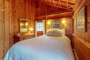 a bedroom with a white bed in a wooden room at Waterfront cabin with ocean view & private dock in East Boothbay