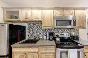a kitchen with a sink and a stove and microwave at New Riverfront Condo in Sheepscot Harbour - Walk to Famed Seafood Eatery in Edgecomb +6 photos