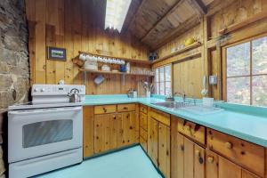 a kitchen with wooden cabinets and a white stove top oven at Waterfront cabin with ocean view & private dock in East Boothbay