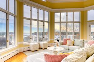 a living room with a couch and windows at Bayfront home with 270-degree views, large deck & porch - near Popham Beach in Phippsburg