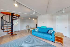 a living room with a blue couch and a spiral staircase at Unique oceanfront home with a deck, tons of natural light, & amazing views in Wiscasset