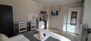 a white room with a bed and a kitchen at Naliya Guest house in Cape Town
