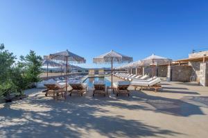 a group of lounge chairs and umbrellas next to a pool at Zefyria Luxury Suites in Zefiría